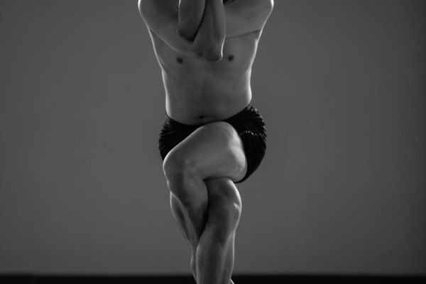 A calm and focused person performing a yoga sequence in a minimalist studio.