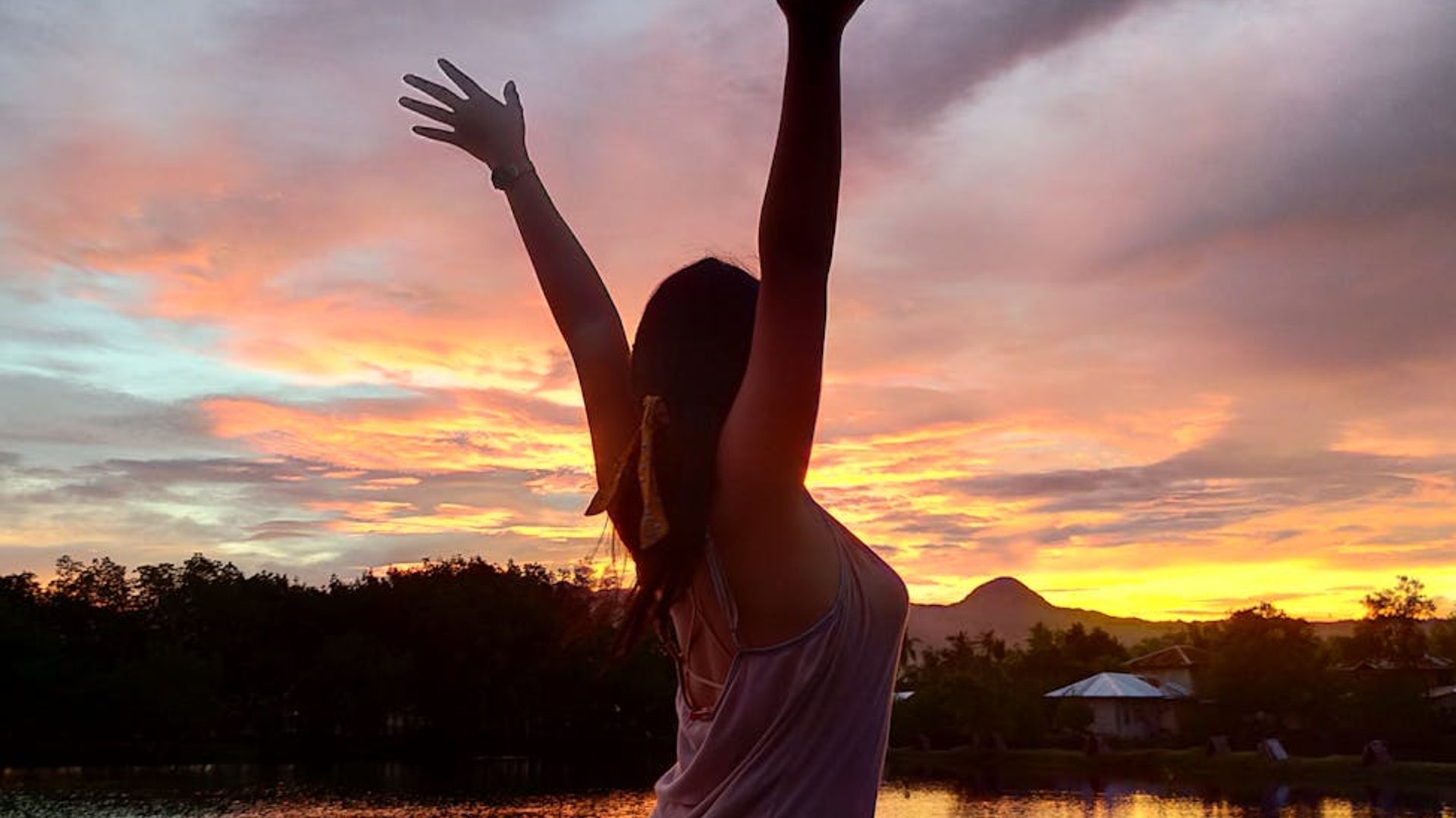Silhouette of a person in a calm yoga pose against a dark, serene background.